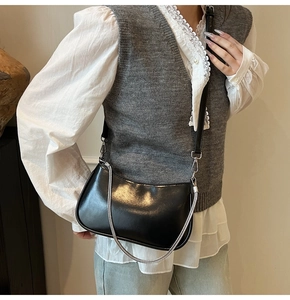 Detail of black leather half-moon shoulder bag with silver chain and slim strap