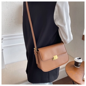 Model wearing a vintage tan crossbody bag with a gold rectangular metal lock detail