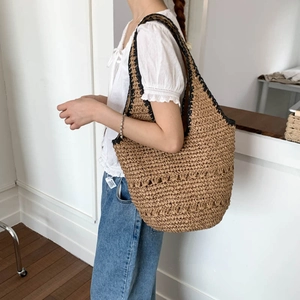 Detail of hand-woven straw tote bag featuring contrast black trim and hollow texture