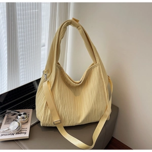 Detail of light yellow pleated tote bag with detachable strap and metallic hardware