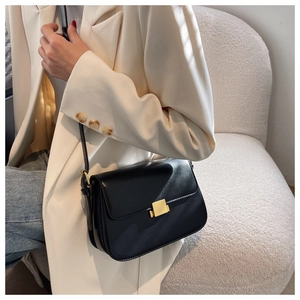 Classic black leather crossbody bag with square gold buckle shown on a model
