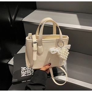 Dettaglio mini borsa bianco crema con ciondolo a cuore di perle e fiocco in pizzo