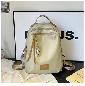 Detail of champagne nylon backpack with leather handle and cute silver bear keychain