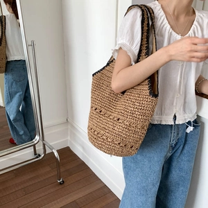 Detail of hand-woven straw tote bag with black crochet handles and light inner lining