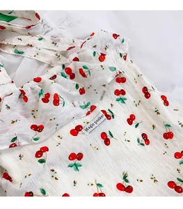 Detailed view of white mesh fabric featuring red cherry prints and ruffle collar texture
