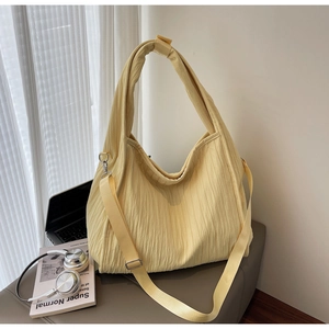 Detail of soft pleated yellow hobo tote bag with wide strap in a cozy desk lifestyle setting