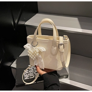 Dettaglio borsa in pelle stropicciata bianco crema con ciondolo a cuore e fiocco pizzo