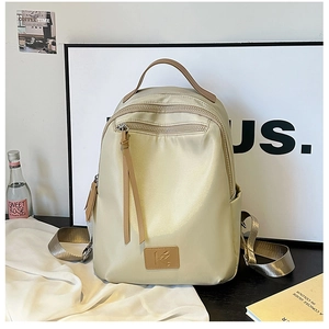 Detail view of cream nylon backpack featuring water-resistant fabric and premium leather logo