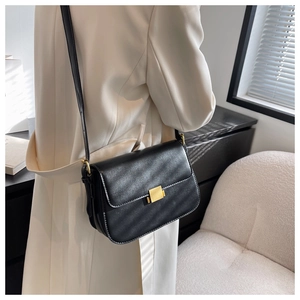Side view of a vintage black leather crossbody bag with a gold buckle worn by a model