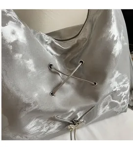 Detail of silver metallic textured tote bag with butterfly zipper and lace-up design