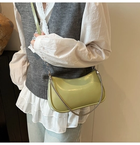 Close-up of avocado green saddle bag with silver chain and leather strap details