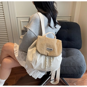 Detail of white and beige nylon backpack showing drawstring closure and brand logo plate