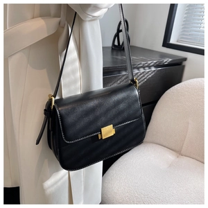 Detail of minimalist black leather crossbody bag with elegant gold metal buckle and strap