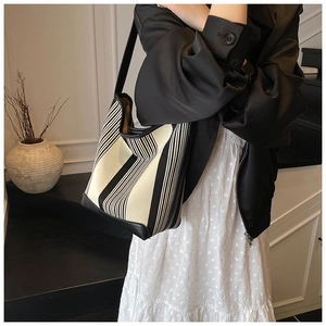 Detail of black and white striped canvas tote with leather straps on model's shoulder