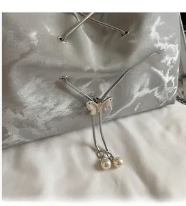 Detail of silver marble tote with metal butterfly drawstring and white pearl charm