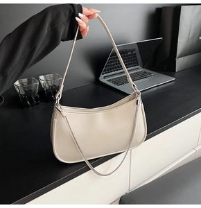 Detail of off-white crescent underarm bag with silver chain strap held by model