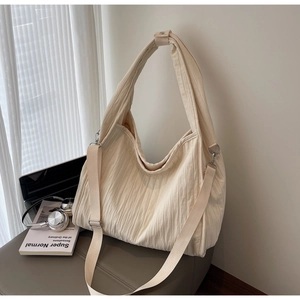 Detail of cream pleated tote bag featuring high-capacity design and adjustable shoulder straps