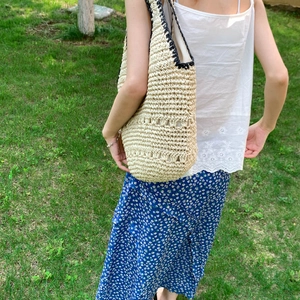 Detail of handmade woven straw tote bag with black trim and hollow decorative pattern