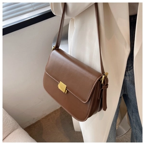 Close-up of vintage brown crossbody bag with gold buckle on a stylish woman