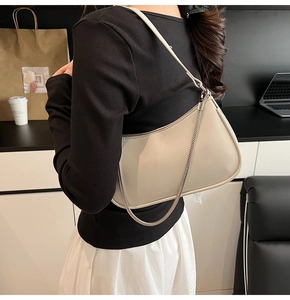 Detailed view of cream hobo bag with silver chain strap worn over woman shoulder
