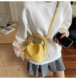 Detail of yellow bucket bag featuring woven handle and lychee grain texture