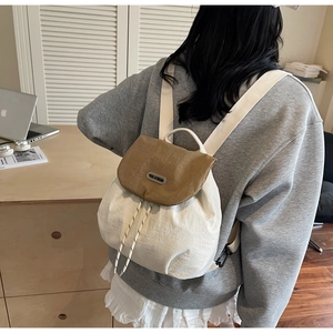 Dettaglio di uno zaino con coulisse beige e kaki indossato da una modella in casa