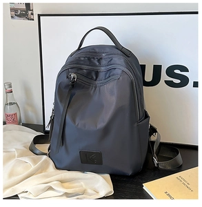 Detail view of large dark grey nylon backpack with multi-layer zippers and side pockets