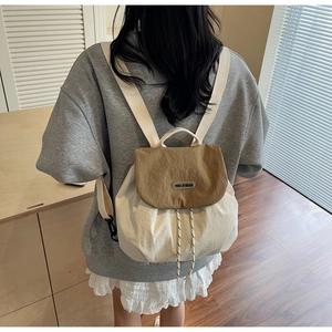 Detail of a minimalist drawstring backpack featuring beige nylon and khaki flap design