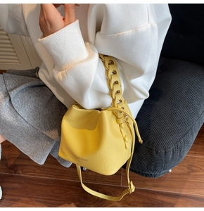 Detail of yellow bucket bag with woven chain handle and lychee texture finish