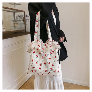 Detail of white mesh tote bag with red cherry print and delicate ruffle trim edge