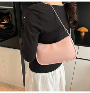 Detail of pink crescent underarm bag with silver chain strap worn by a model