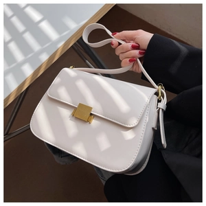Close-up of minimalist beige flap shoulder bag with gold metal clasp and leather texture