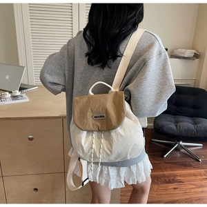Close-up of the contrasting khaki and beige drawstring backpack worn by a model