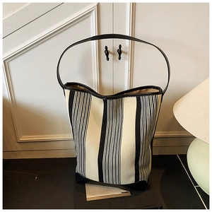 Detail of black and white striped canvas tote bag with premium leather trim and handles