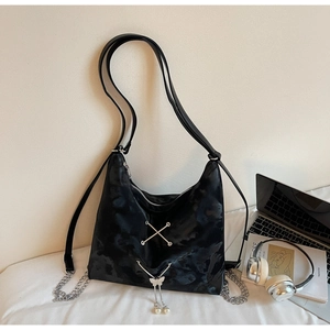 Detail of black cloud-textured tote with silver cross-straps and pearl butterfly charm