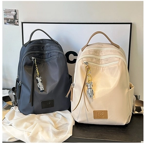 Close-up of minimalist nylon travel backpacks with metal bear charms and zipper details