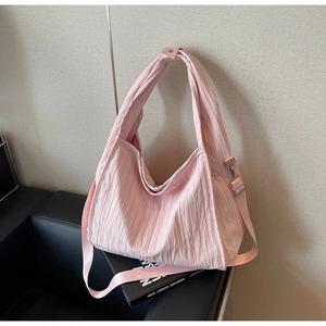 Detail of pink pleated fabric texture and silver metal hardware on large shoulder bag