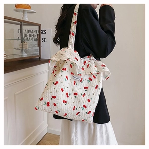 Close-up of white mesh tote bag featuring red cherry patterns and ruffle trim detail