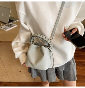 Detailed view of light blue lychee pattern bucket bag with woven handle on shoulder