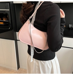 Close-up of a pink semi-circular shoulder bag with silver chain and leather strap on model
