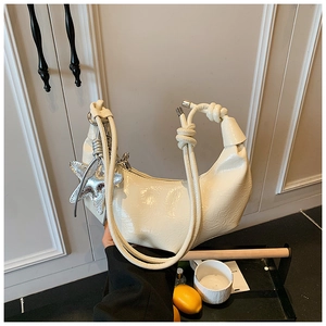 Détail du sac plissé crème avec breloque étoile et bandoulière nouée
