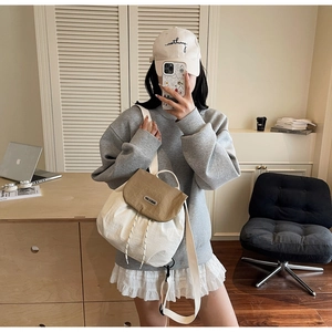 Mirror selfie showing a woman wearing a beige nylon bucket backpack with brown flap detail