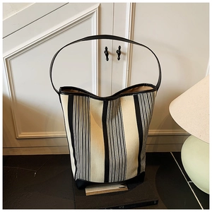 Detail view of the thick striped canvas texture and reinforced black strap of the tote bag