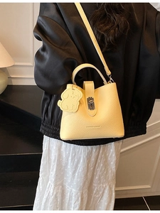 Borsa a secchiello in pelle giallo tenue con ciondolo a cane e chiusura in metallo