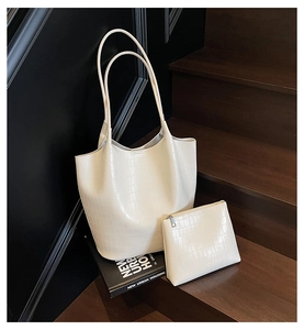 Close-up of vintage crocodile-embossed bucket tote bag set in cream white leather