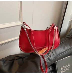 Detail of red leather underarm bag featuring silver chain and adjustable shoulder strap