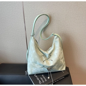 Detail of mint green tie-dye hobo bag with metal eyelets and butterfly pearl charm