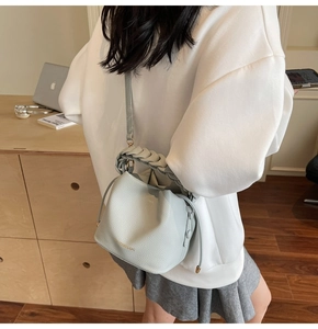 Detail of light blue bucket bag with wide woven handle and drawstring closure shown in home