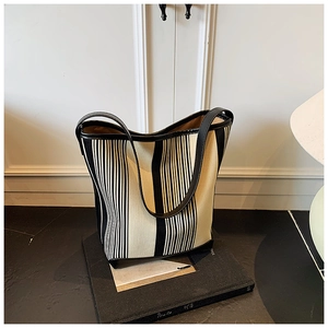 Detail view of the black and white vertical striped canvas tote bag with leather straps