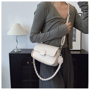 Detail of creamy white crossbody bag showing lychee grain leather and woven chain strap